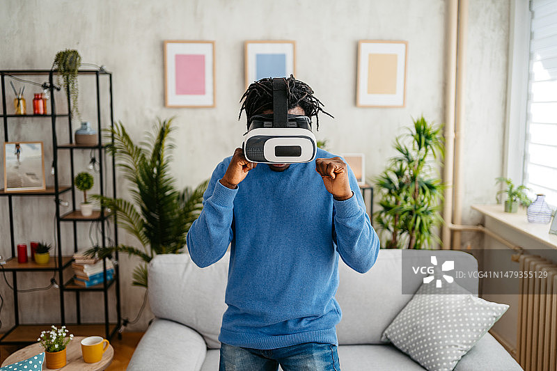 在家戴VR头显玩拳击游戏的年轻男人图片素材