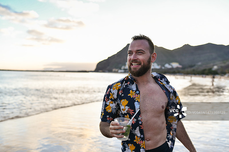 在西班牙特内里费圣克鲁斯海滩享受日落和莫吉托的休闲男子图片素材