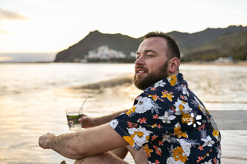 在西班牙特内里费岛圣克鲁斯，英俊男子一边喝莫吉托，一边感受夏日海滩的微风图片素材