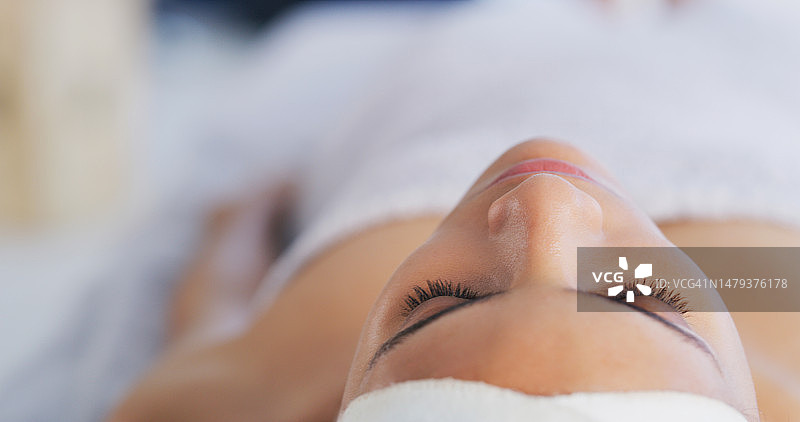 在床上的女性的面部、水疗和放松，躺下来享受健康、奢华的护理或周末度假期间的平静。按摩、健康或美容，以及在沙龙里做睫毛延长术的年轻女性图片素材