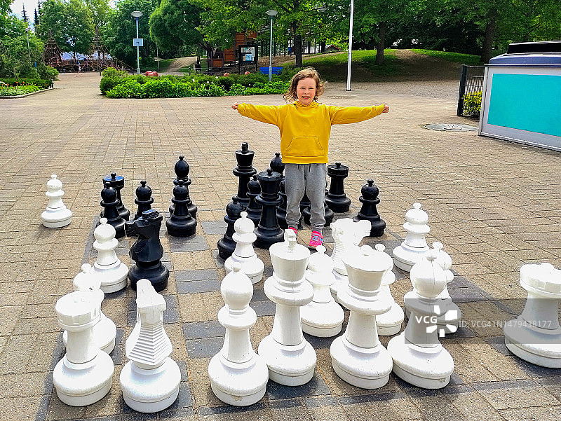 在公园游乐场玩巨型象棋的6岁白人儿童女孩图片素材
