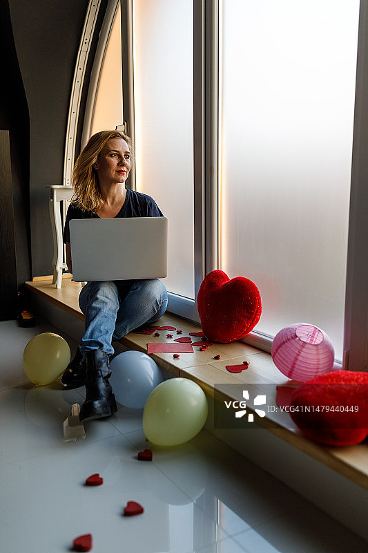 坐在窗台上用笔记本电脑，思念爱人的女人图片素材