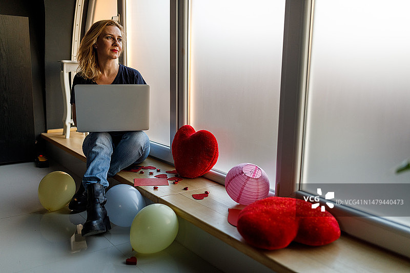坐在窗台上用笔记本电脑，思念爱人的女人图片素材