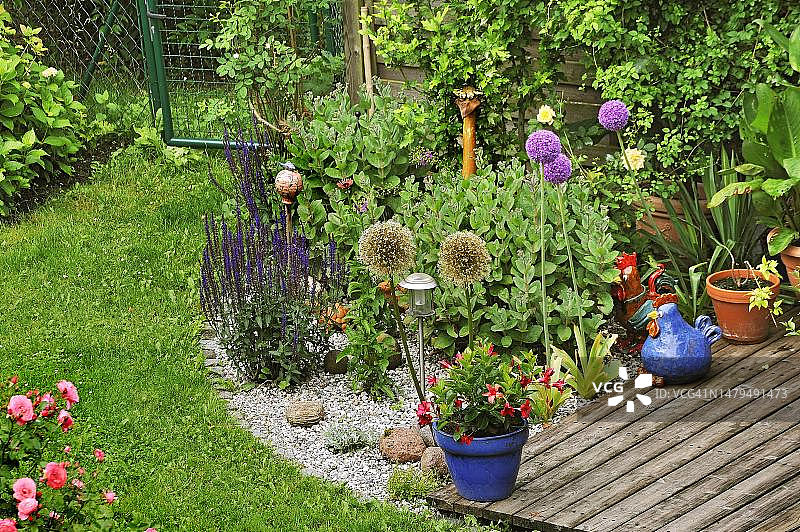 德国巴伐利亚慕尼黑花园一角，有花卉和陶土雕塑图片素材