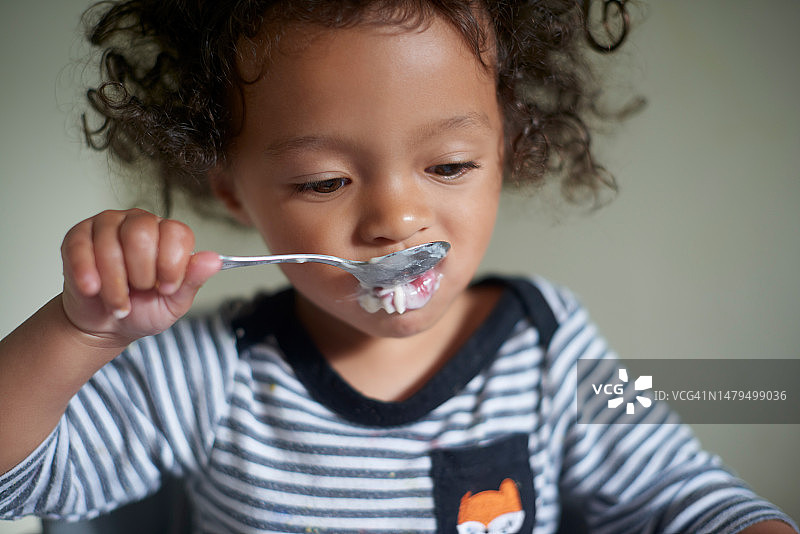 早餐，孩子用勺子狼吞虎咽地吃东西，早上饥饿地品尝食物。健康、饥饿和婴儿的脸，享受并在房子里自己喂午餐、晚餐或美味佳肴图片素材
