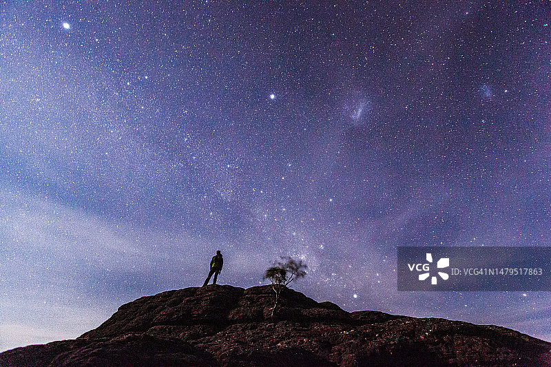 男人站在山丘上，夜晚仰望星空图片素材