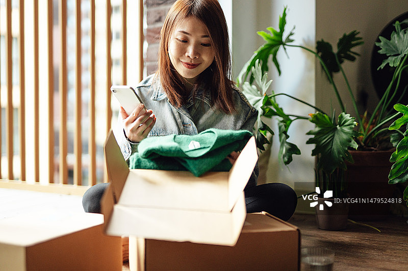 年轻亚裔女性在家拆包裹图片素材