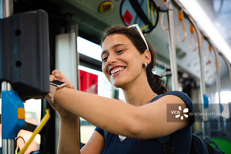 快乐女孩在旅途中使用智能手表购买火车票的肖像图片素材