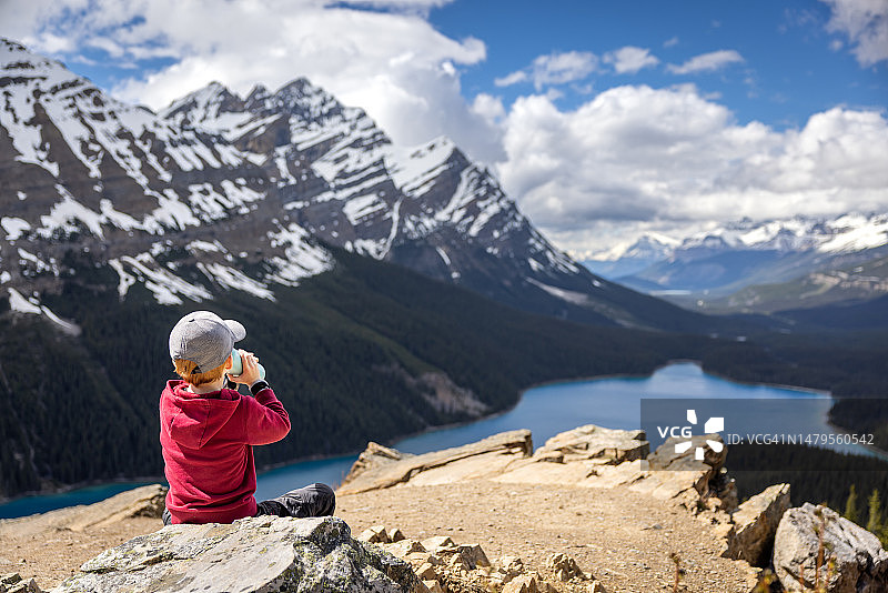 在加拿大艾伯塔省沛托湖休息和喝水的年轻红发男孩图片素材