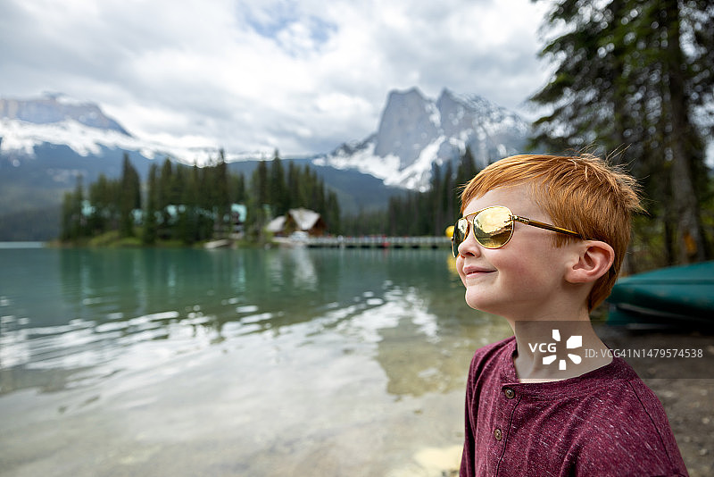快乐可爱的红发男孩在夏日翡翠湖边微笑图片素材