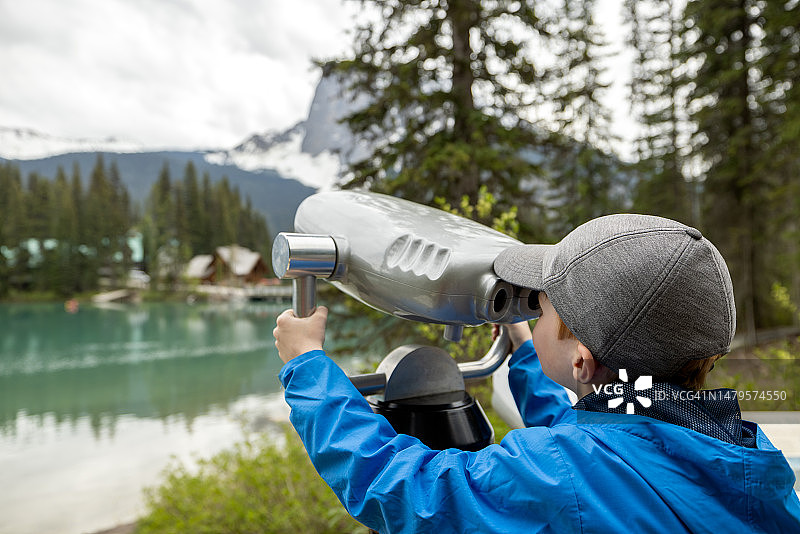 在加拿大不列颠哥伦比亚省的翡翠湖用双筒望远镜观察的男孩图片素材