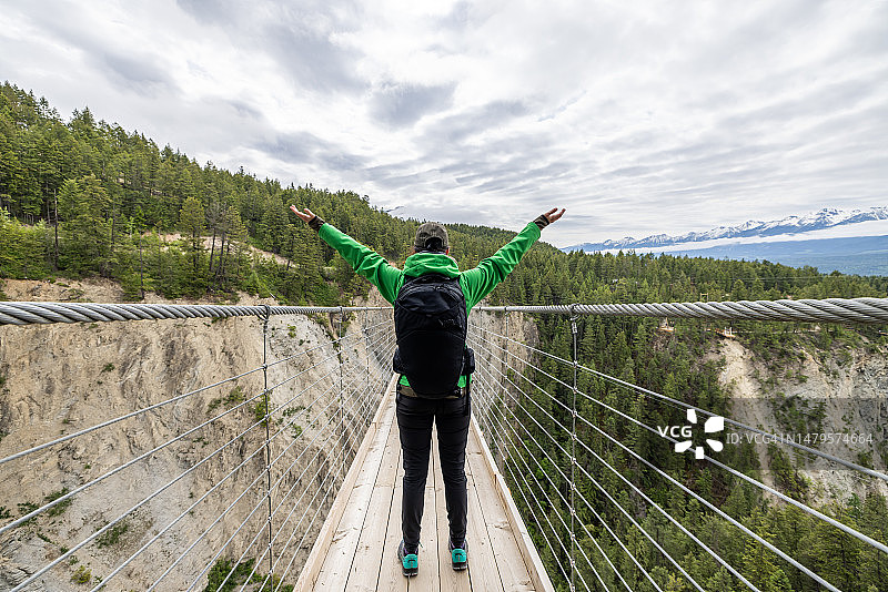 年轻女人走过木制吊桥图片素材