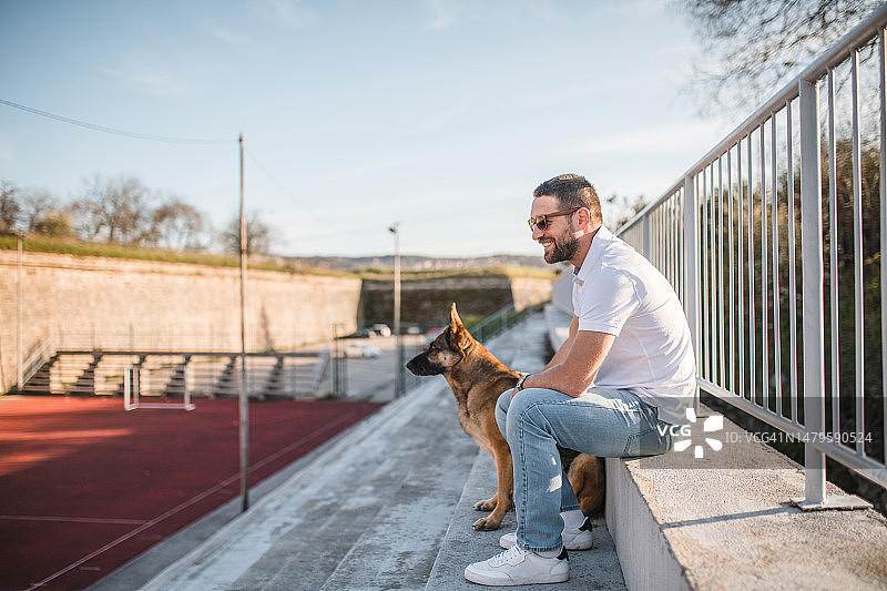 侧面视角：德国牧羊犬和微笑的男主人一起享受美好的一天图片素材