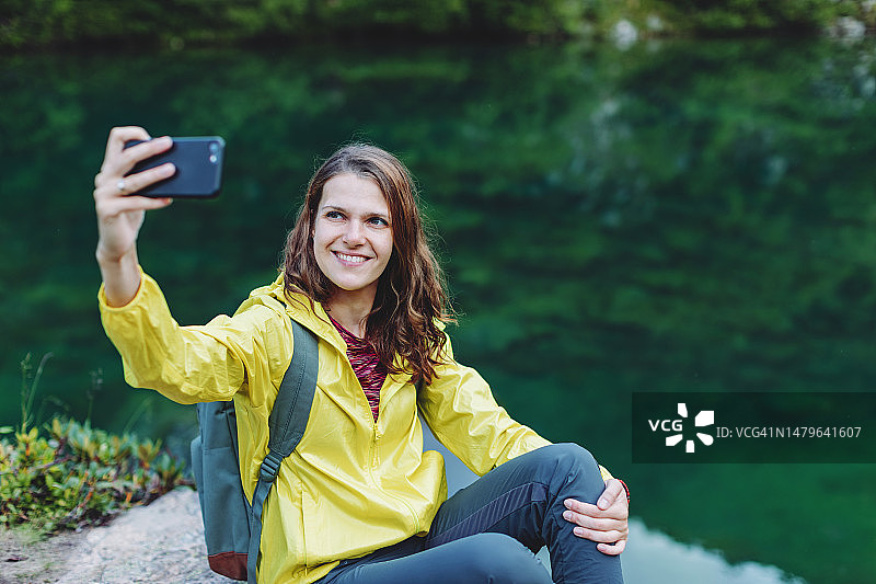 在山间湖泊使用手机的年轻女子图片素材