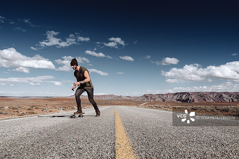 男人在纪念碑谷玩滑板。图片素材