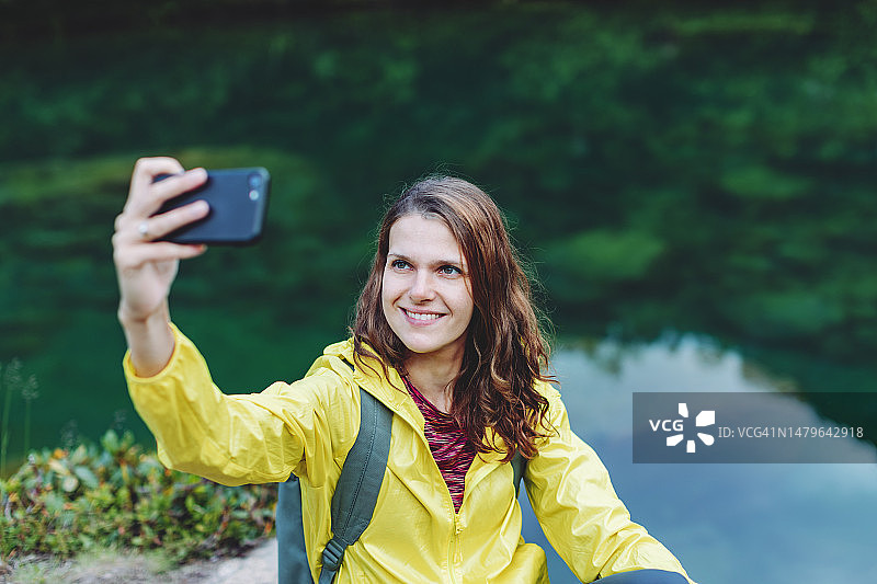 在山间湖泊使用手机的年轻女子图片素材