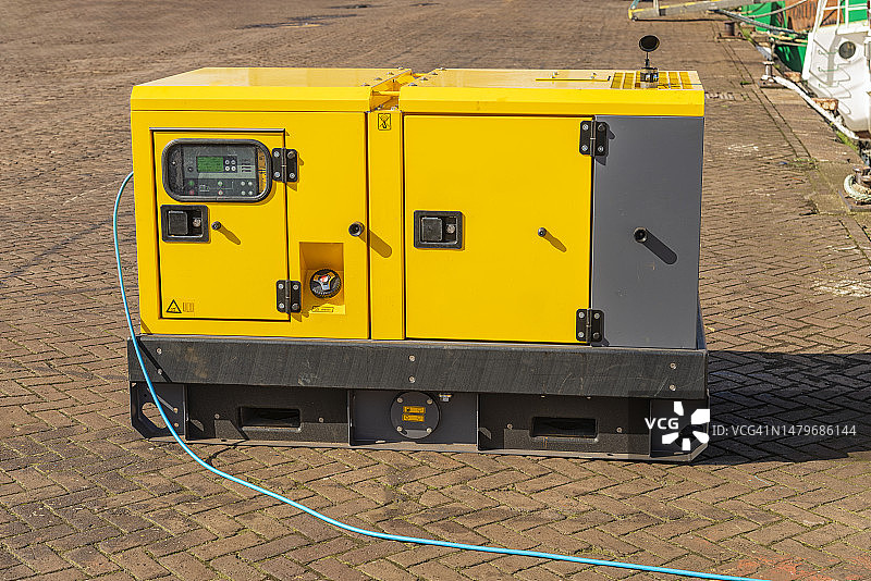 停靠在港口码头上的大型黄色钢铁柴油发电机图片素材
