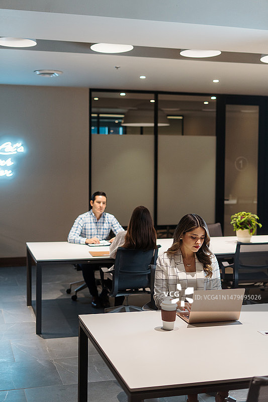 在共享办公空间里，年轻的拉丁裔人在桌旁工作图片素材
