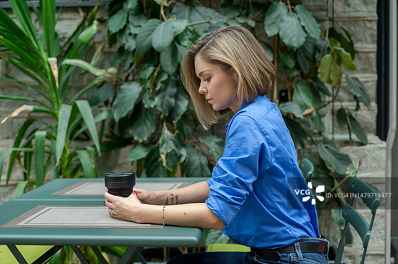 女商人从可重复使用的杯子里喝咖啡，在街边咖啡馆露台上图片素材