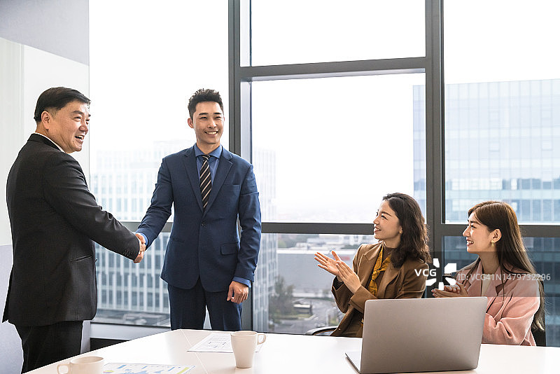 在现代办公室里握手的女商人和商人图片素材