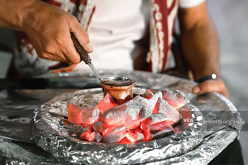 用煤炭在土耳其咖啡壶中烹制土耳其咖啡，男人的手部特写图片素材