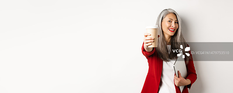 笑容满面的亚洲女商人递上一杯咖啡图片素材