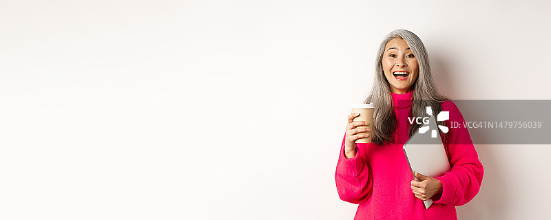 快乐的亚洲老年女企业家喝着咖啡开怀大笑图片素材