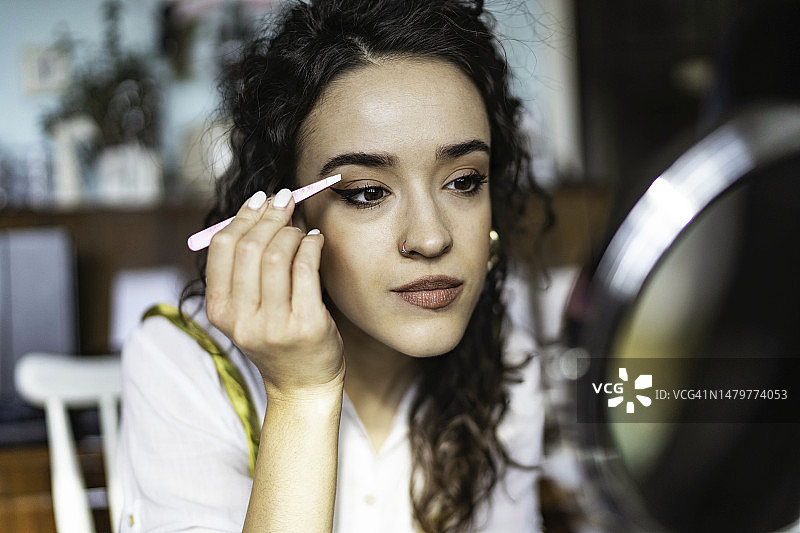 专注的女人在拔眉毛图片素材