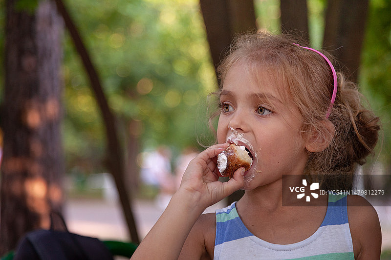 在公园里吃奶油泡芙的小女孩图片素材