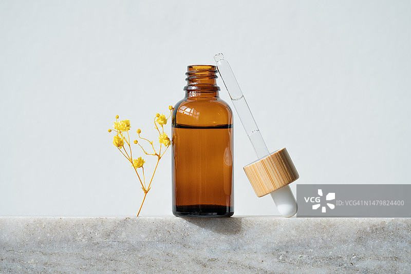 大理石台上带有滴管的琥珀色瓶子图片素材