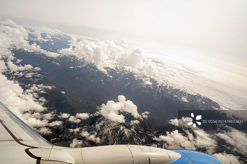 飞机舷窗外的天空、云彩和山脉，度假或商务旅行图片素材