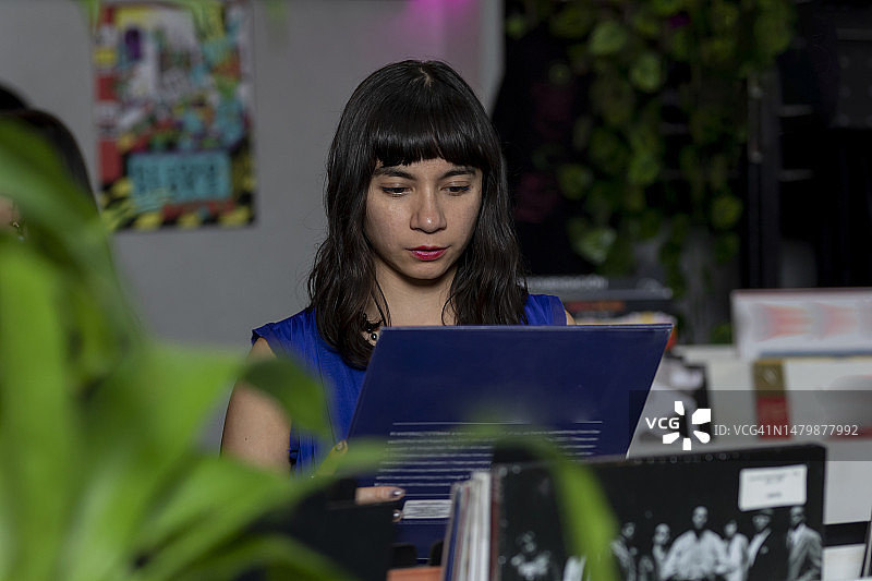 年轻女子在商店里查看黑胶唱片的封面图片素材