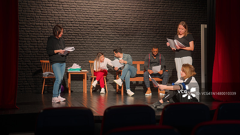 一群舞台表演者在检查文本和排练图片素材