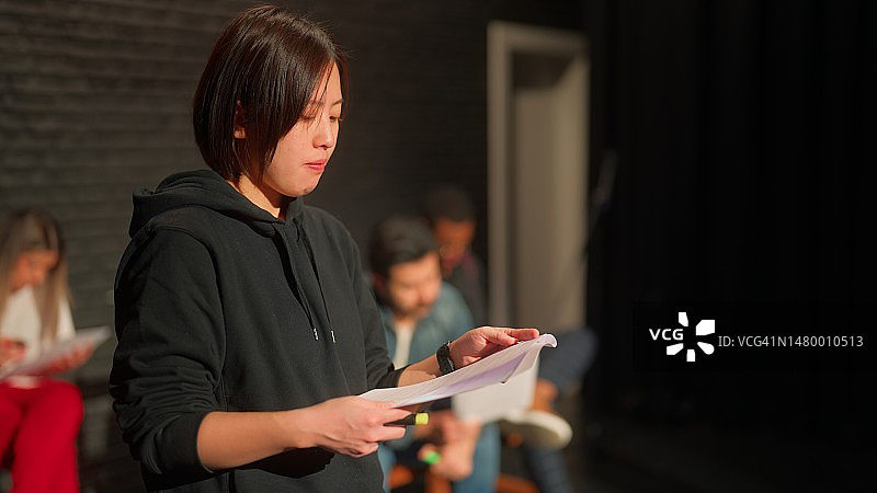 在舞台上阅读并检查剧本的戏剧女演员图片素材