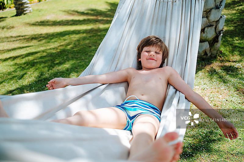 赤脚的男孩在吊床上小憩图片素材