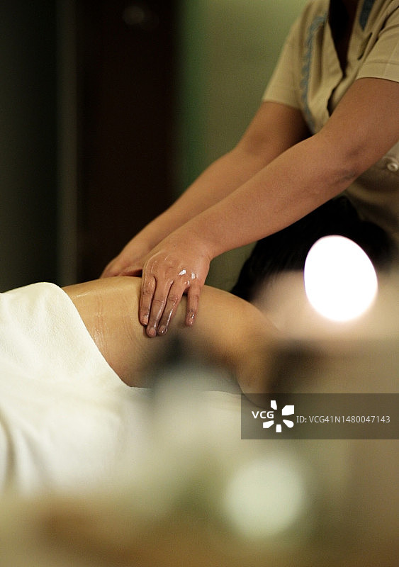 按摩理疗师用精油为女性进行背部和肩部按摩，享受放松的SPA体验图片素材