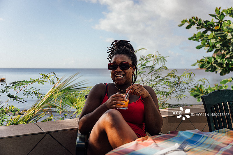 女人在俯瞰加勒比海的户外餐厅喝饮料图片素材