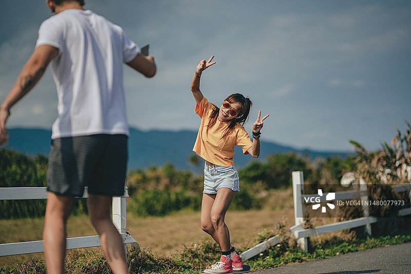 两个亚洲好友在户外一起玩滑板，用智能手机记录并上传到社交媒体图片素材