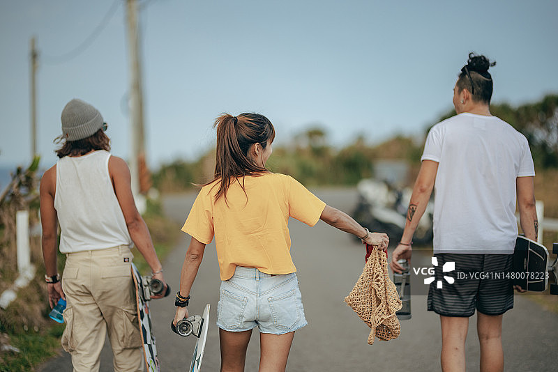 三位亚洲滑板爱好者准备整理滑板工具回家图片素材