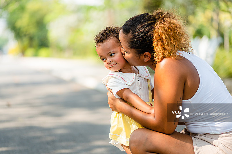 年轻黑人母亲在公园里拥抱女儿图片素材