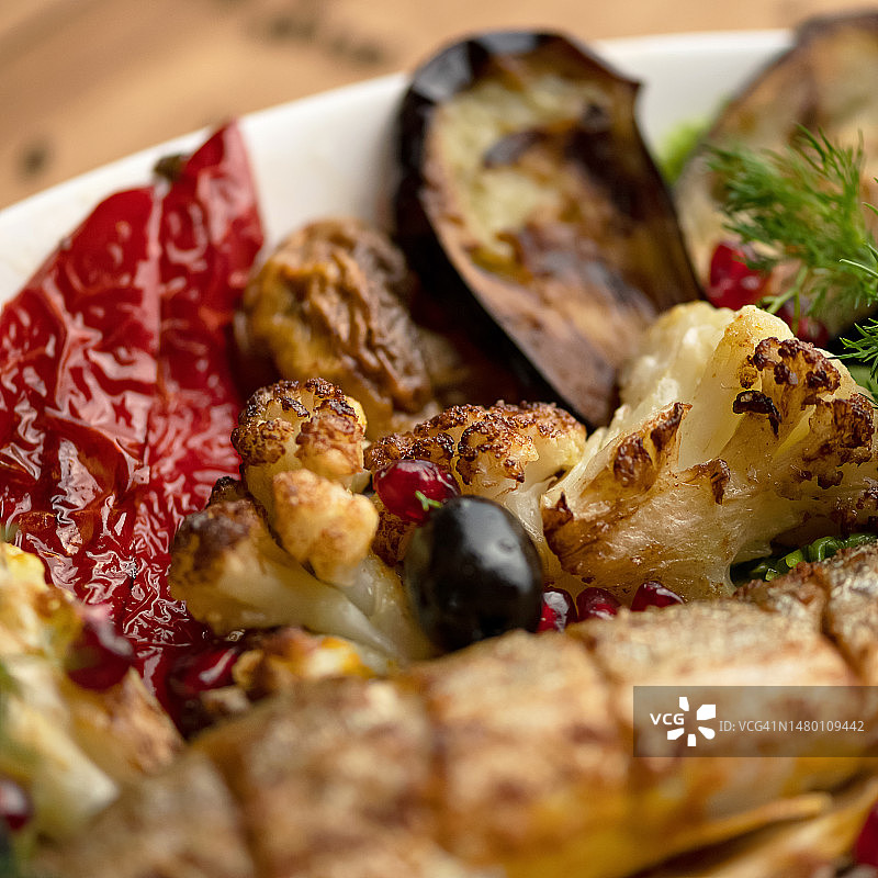 白色盘子里的烤蔬菜：烤花椰菜、西红柿、橄榄、茄子，用莳萝装饰图片素材