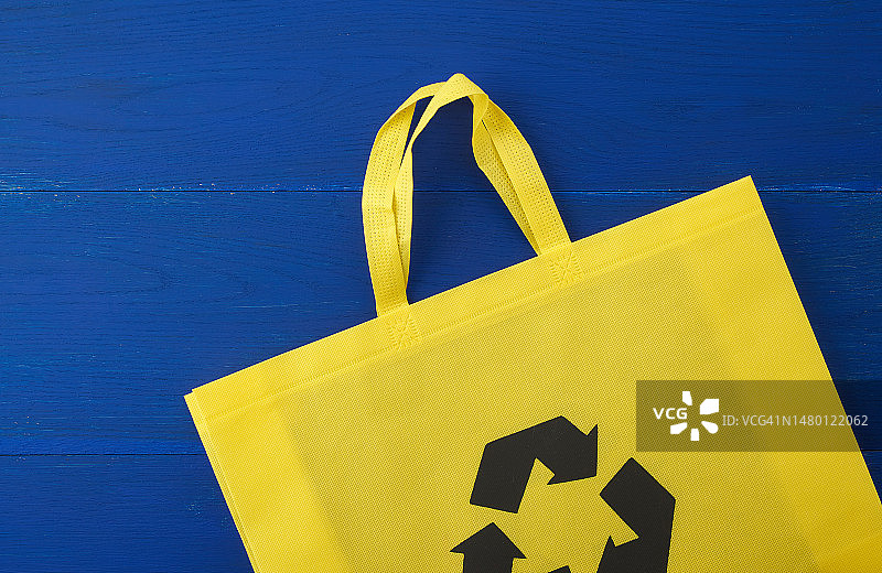 罗马尼亚蓝色木质背景上的黄色粘胶纤维可重复使用袋子图片素材