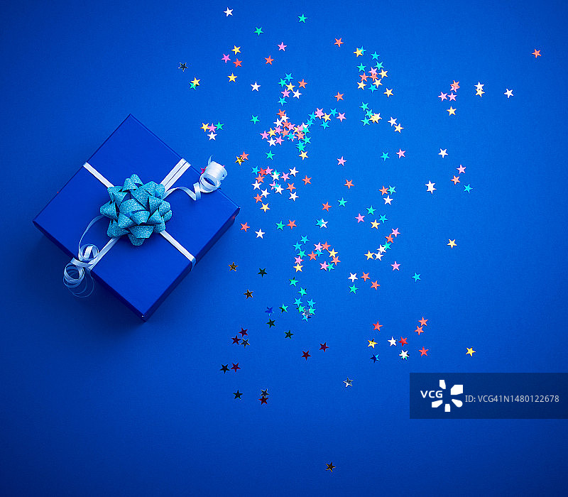 蓝色背景上带蝴蝶结和彩色闪光的方形蓝色闪亮盒子，罗马尼亚图片素材