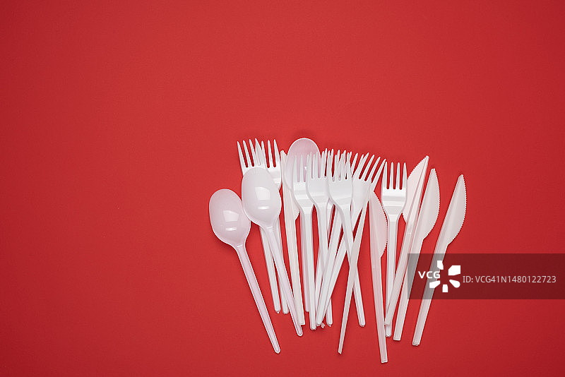 成堆的塑料叉子和勺子，红色背景，顶视图图片素材
