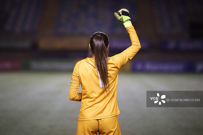 比赛前，举起拳头的女足球守门员的背影图片素材