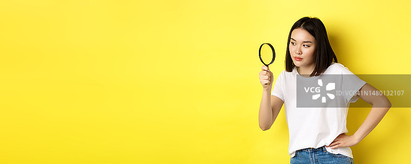 拿着放大镜、充满好奇的亚洲女侦探图片素材