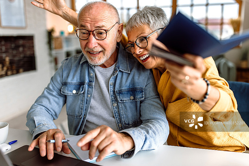 老年夫妇准备旅行，在笔记本电脑上做计划图片素材
