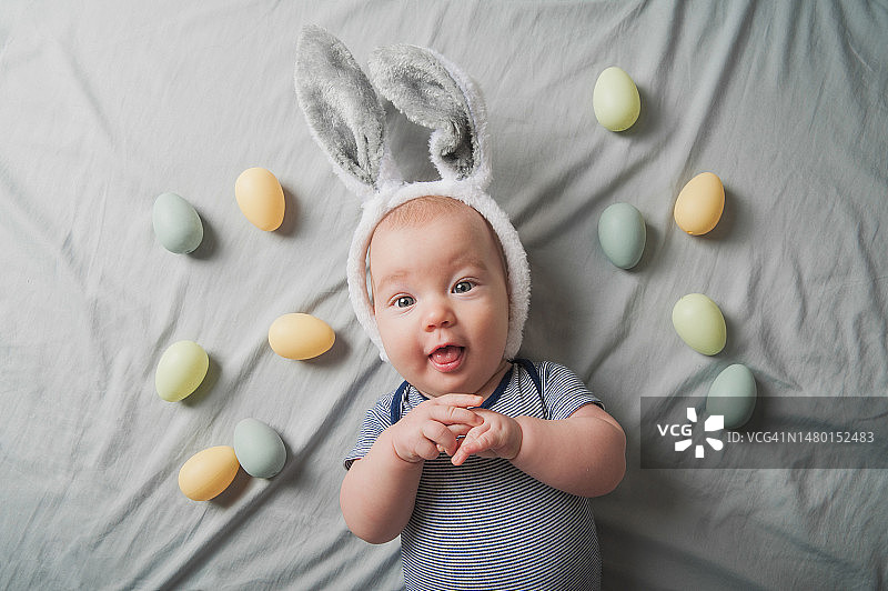 床上与复活节彩蛋和兔子耳朵在一起的四个月大新生儿图片素材