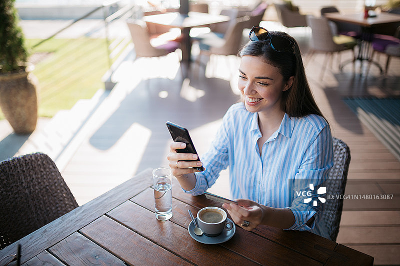 在咖啡店享受网上购物的迷人白人女性图片素材
