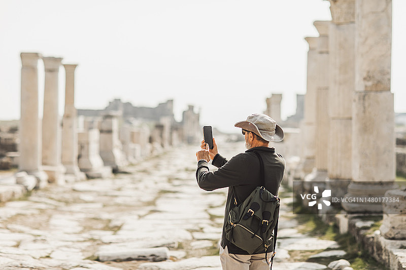 老年男人用手机拍摄古董旅游地标后视图图片素材